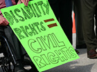 person in wheelchair holding sign saying disability rights equal civil rights
