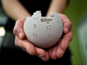 closeup of two hands holding Wikipedia globe