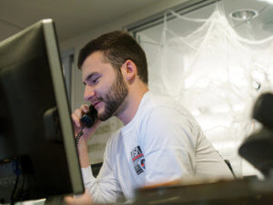 Student worker at computer screen talking on telephone